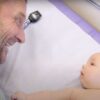 Dr. Paul Thomas works on getting a smile out of a 2-month-old baby (image from "A Crazy Day in the LIfe of a Busy Pediatrician" on Dr. Paul's YouTube channel).